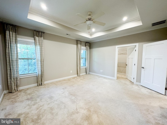 unfurnished bedroom featuring multiple windows, ornamental molding, light colored carpet, and a raised ceiling