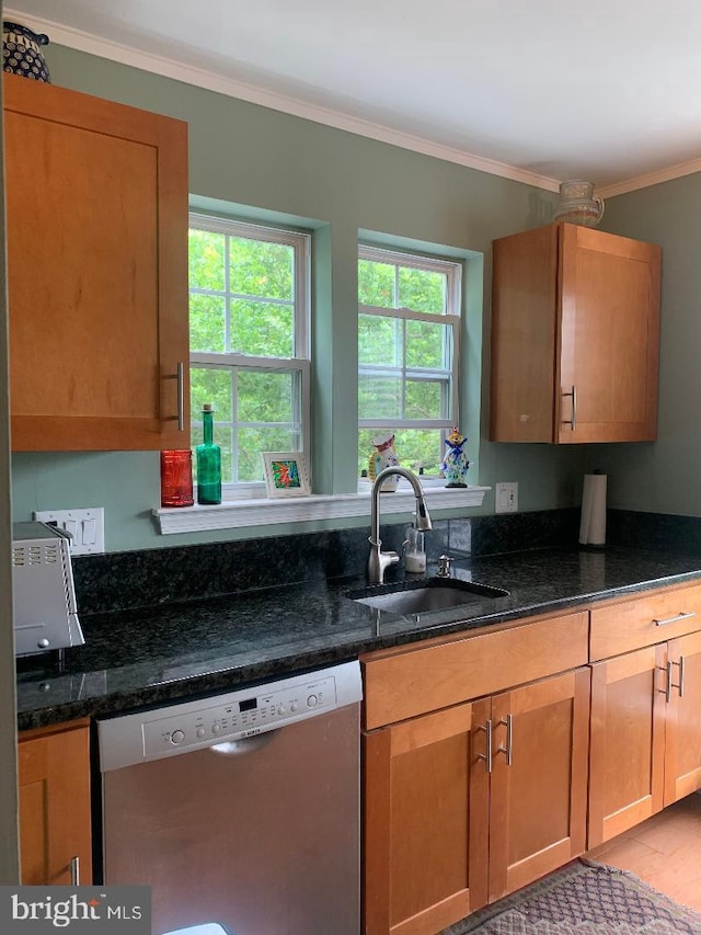 kitchen with sink, crown molding, dark stone countertops, stainless steel dishwasher, and a healthy amount of sunlight