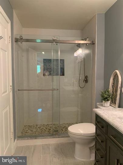 bathroom with walk in shower, vanity, and toilet