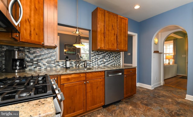 kitchen featuring sink, decorative light fixtures, appliances with stainless steel finishes, light stone countertops, and decorative backsplash