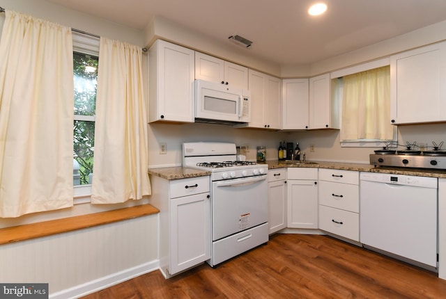 kitchen featuring sink, white appliances, white cabinets, dark hardwood / wood-style flooring, and dark stone counters