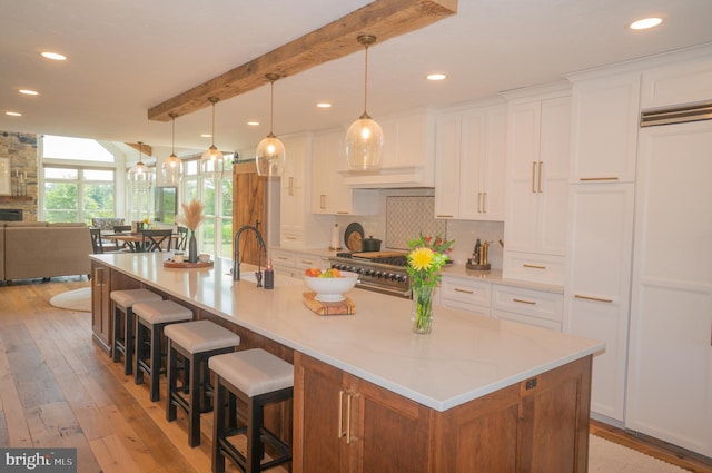 kitchen with decorative light fixtures, tasteful backsplash, white cabinetry, beamed ceiling, and a spacious island