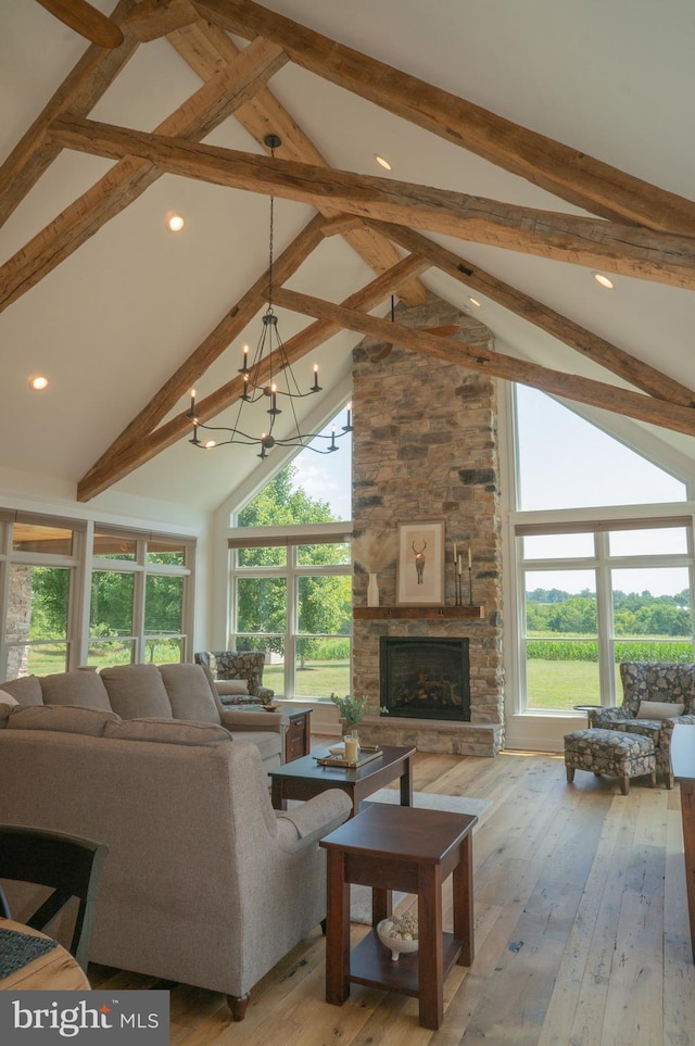 living room with a stone fireplace, a chandelier, high vaulted ceiling, beam ceiling, and hardwood / wood-style floors