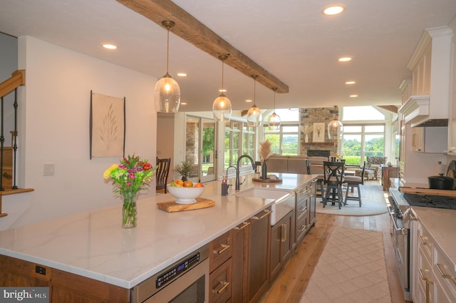 kitchen featuring pendant lighting, sink, a spacious island, a fireplace, and high end stove