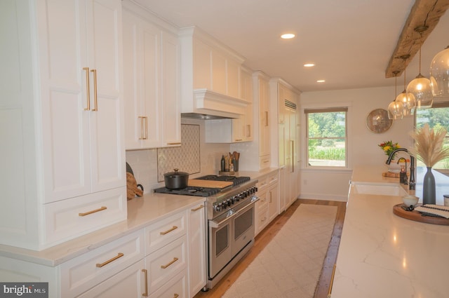 kitchen featuring sink, light stone countertops, white cabinets, and range with two ovens