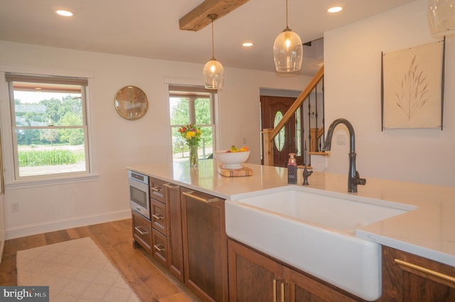 kitchen with plenty of natural light, sink, stainless steel microwave, and decorative light fixtures