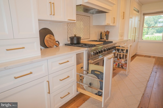 kitchen with backsplash, custom exhaust hood, white cabinets, and light wood-type flooring