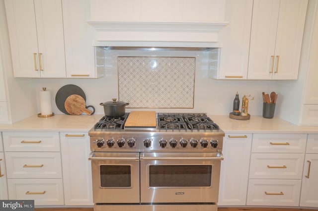 kitchen featuring white cabinetry, double oven range, and backsplash