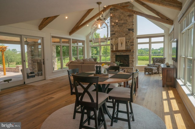 dining space with hardwood / wood-style flooring, a fireplace, high vaulted ceiling, and beamed ceiling