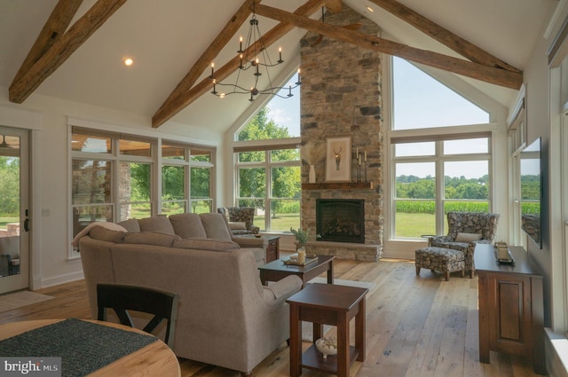 living room with light hardwood / wood-style flooring, beam ceiling, high vaulted ceiling, a stone fireplace, and a chandelier