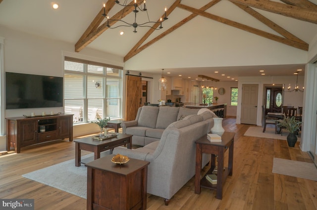 living room with a barn door, a chandelier, and light hardwood / wood-style floors