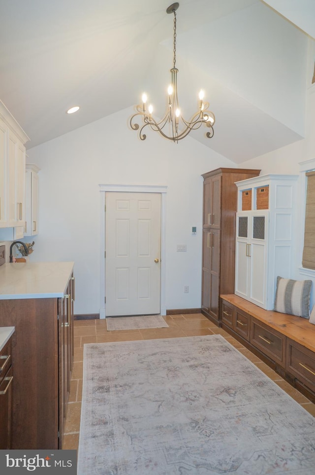 mudroom with lofted ceiling, light tile patterned floors, and an inviting chandelier