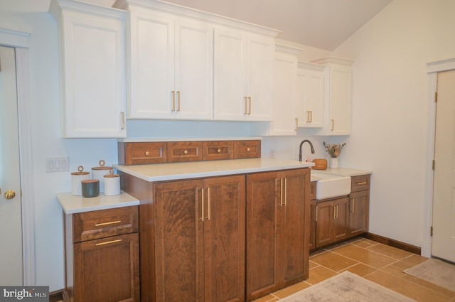 kitchen featuring sink, light tile patterned floors, and white cabinets