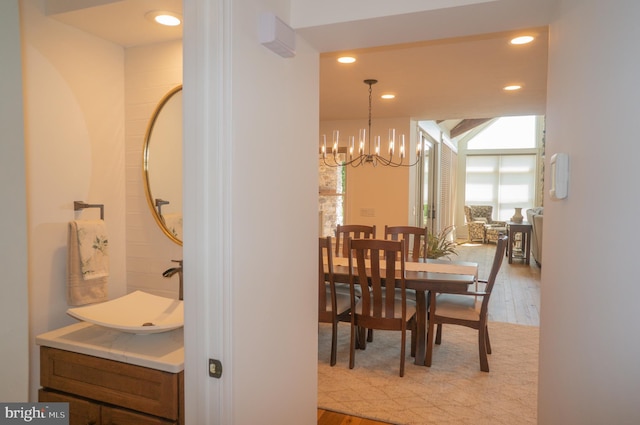 dining space with sink, light hardwood / wood-style flooring, and a notable chandelier