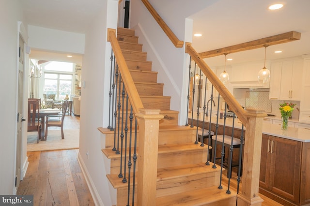 stairs featuring beam ceiling and wood-type flooring