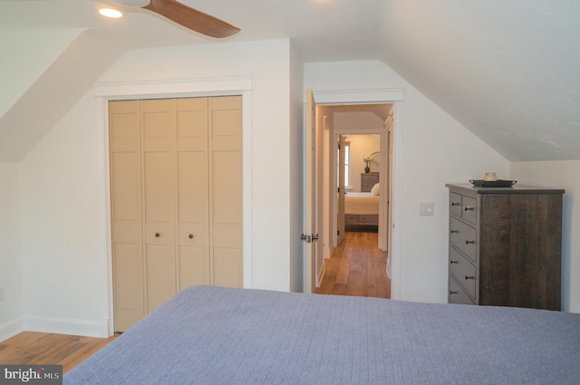 bedroom with a closet, vaulted ceiling, ceiling fan, and light hardwood / wood-style flooring