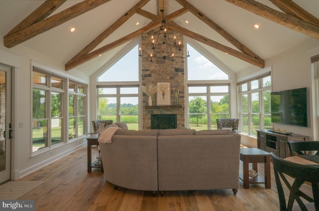 living room featuring high vaulted ceiling, a notable chandelier, a fireplace, and light hardwood / wood-style floors