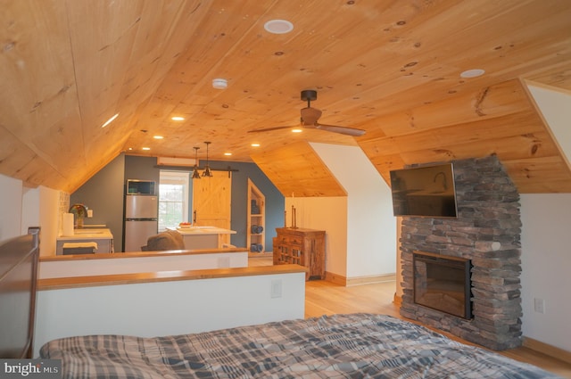 interior space featuring wood ceiling, vaulted ceiling, a stone fireplace, and light wood-type flooring