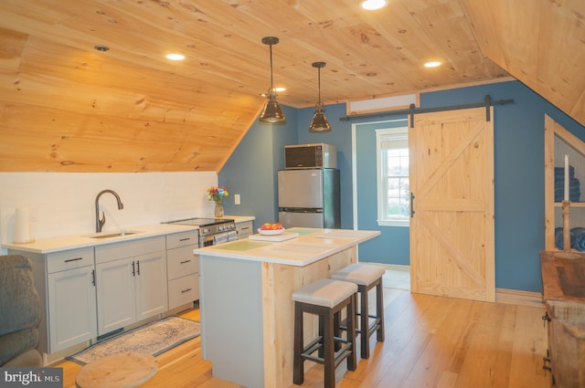 kitchen featuring sink, stainless steel fridge, hanging light fixtures, a center island, and a barn door