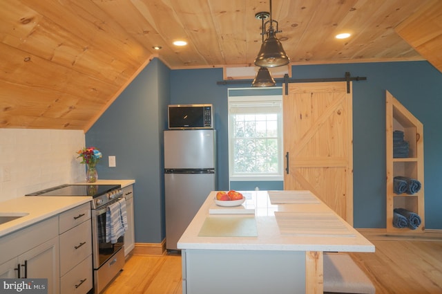 kitchen featuring appliances with stainless steel finishes, hanging light fixtures, wood ceiling, light hardwood / wood-style floors, and a barn door