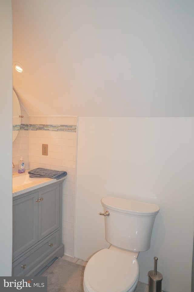 bathroom with vanity, tile walls, and toilet