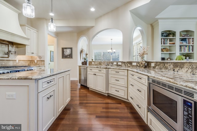 kitchen with premium range hood, a kitchen island, appliances with stainless steel finishes, white cabinets, and light stone countertops