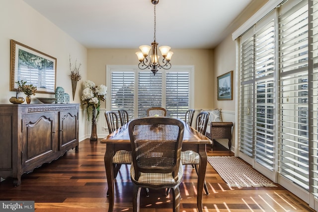 dining space with dark hardwood / wood-style flooring and a notable chandelier