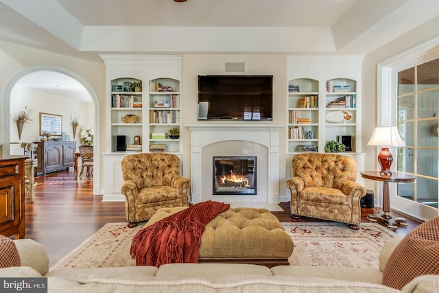 sitting room featuring built in shelves and dark hardwood / wood-style floors