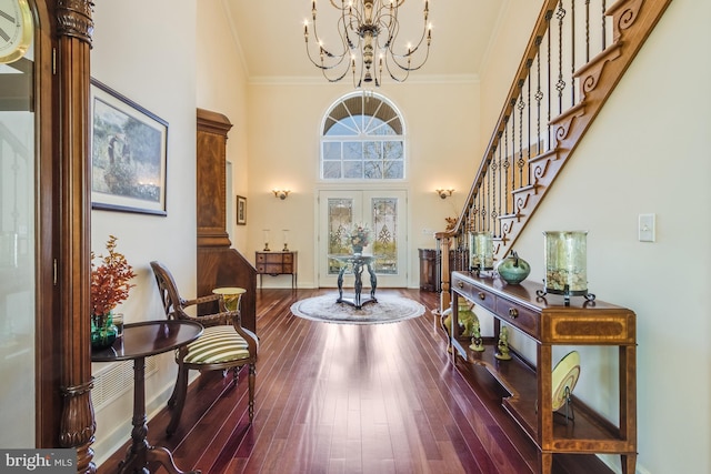 foyer with a notable chandelier, hardwood / wood-style flooring, ornamental molding, and french doors