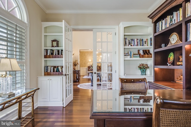 living area with crown molding, dark hardwood / wood-style floors, a healthy amount of sunlight, and built in shelves