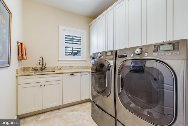 clothes washing area with cabinets, sink, and washer and clothes dryer