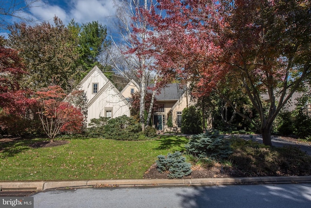 view of property hidden behind natural elements featuring a front lawn