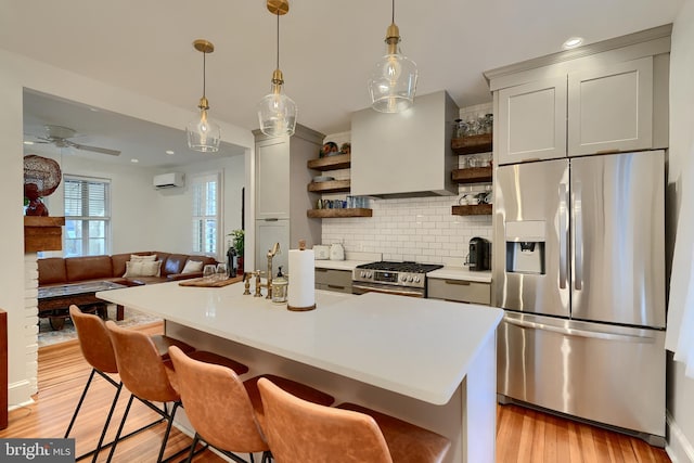 kitchen featuring appliances with stainless steel finishes, tasteful backsplash, a wall mounted AC, a breakfast bar area, and wall chimney range hood