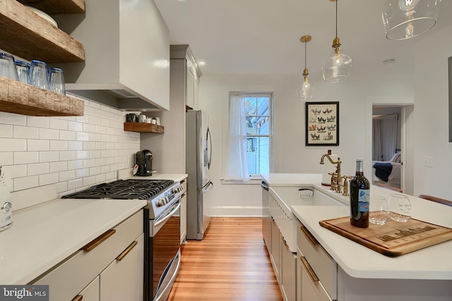 kitchen featuring decorative light fixtures, light hardwood / wood-style flooring, custom range hood, stainless steel appliances, and white cabinets