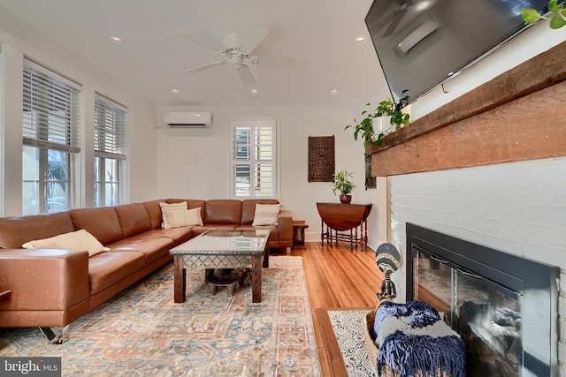 living room with ceiling fan, a fireplace, a wall mounted AC, and hardwood / wood-style floors