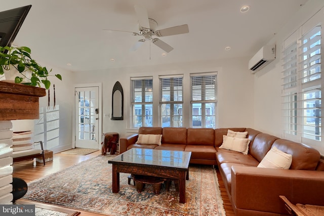 living room featuring an AC wall unit, ceiling fan, and light wood-type flooring