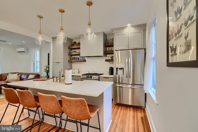 kitchen featuring an AC wall unit, a kitchen bar, a kitchen island with sink, stainless steel appliances, and custom range hood