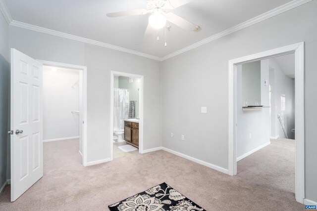 unfurnished bedroom featuring light carpet, connected bathroom, a spacious closet, and crown molding