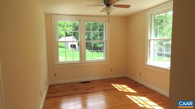 spare room with ceiling fan, a healthy amount of sunlight, and light hardwood / wood-style floors