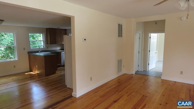 unfurnished room with ceiling fan, sink, and light wood-type flooring