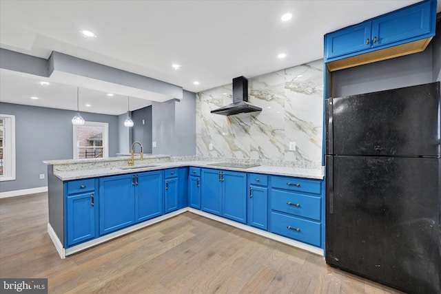 kitchen featuring sink, hardwood / wood-style flooring, hanging light fixtures, black appliances, and exhaust hood