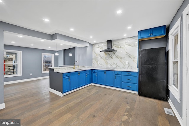 kitchen with wall chimney range hood, blue cabinets, sink, and black appliances