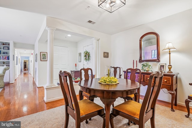 dining room featuring light hardwood / wood-style floors and ornate columns