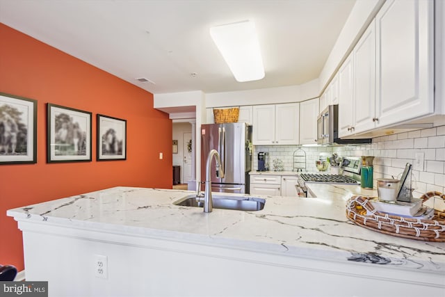 kitchen with white cabinetry, sink, decorative backsplash, stainless steel appliances, and light stone countertops