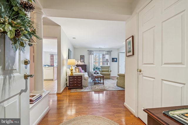 hallway featuring decorative columns and light hardwood / wood-style flooring