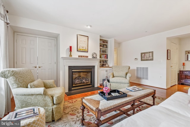 living room with built in shelves and light hardwood / wood-style floors