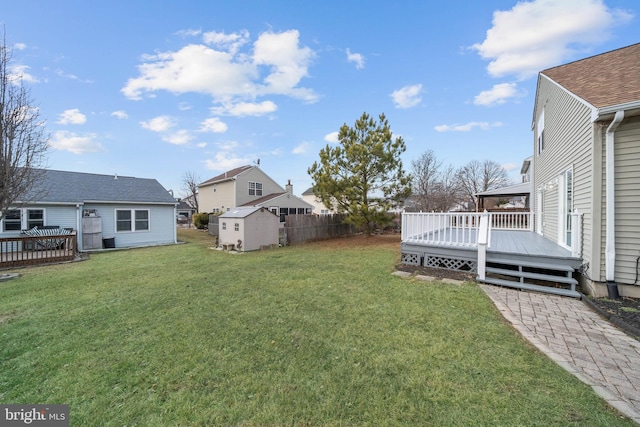 view of yard featuring a wooden deck and a storage shed