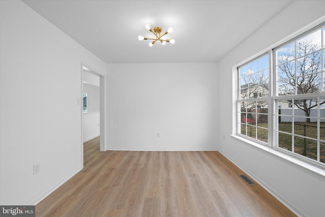 empty room featuring an inviting chandelier and light hardwood / wood-style floors