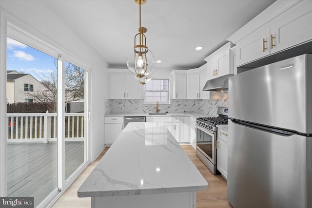 kitchen with sink, hanging light fixtures, appliances with stainless steel finishes, a kitchen island, and white cabinets