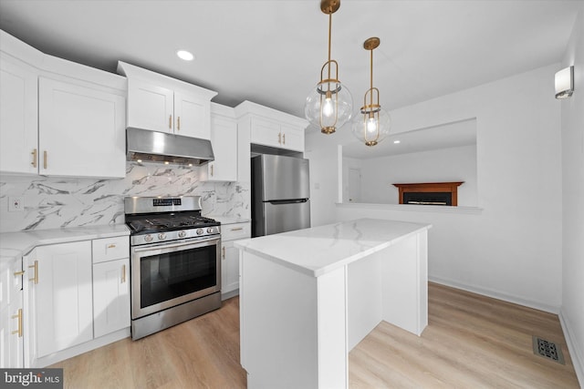 kitchen featuring a kitchen island, appliances with stainless steel finishes, hanging light fixtures, and white cabinets